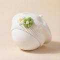 Detail of white knit baby beret featuring handcrafted green and white crochet flowers - Beige