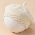 Detailed close-up of cream knit baby beret with textured ribbing and top stem detail - Beige