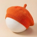 Close-up of orange knitted baby beret showing textured wool fabric and ribbed edge detail - Orange