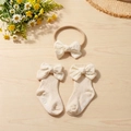 Detail of cream cotton baby bow socks and headband set on a rustic wooden background - Beige