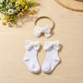 Flat lay of baby headband and socks with bows on light wood texture with daisy flower - White