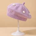 Detalle de una boina de punto lila para bebé con pompones blancos y textura suave - Morado