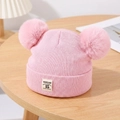 Close-up of pink knit baby hat featuring double faux fur pom-poms and MOONLIGHT label - Pink