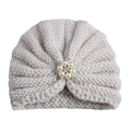 Detailed macro view of cream knitted baby turban hat with elegant pearl and rhinestone flower - Adjustable / Off White