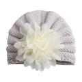 Détail d'un bonnet tricoté pour bébé avec une grande fleur en mousseline sur le dessus - Taille unique / Beige