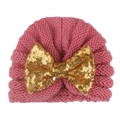 Close-up of pink knit baby beanie featuring a large golden sequin bow decoration - Dusky Pink