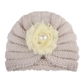 Détail du bonnet tricoté pour bébé avec fleur en mousseline et perle sur tissu beige - Beige