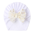 Macro detail of white ribbed baby turban hat with a gold polka dot chiffon bow - White