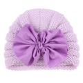 Close-up of a lavender knit baby hat featuring a large decorative dark purple fabric bow - Purple