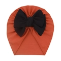 Detail of baby turban hat with a large black textured bow on caramel knit fabric - Orange