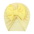 Close-up of soft yellow baby beanie featuring a large textured honeycomb bow decoration - Beige