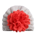 Detailed close-up of cream knit baby hat with a large red decorative lace flower - Adjustable / Beige