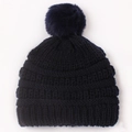 Detail of navy blue cable knit baby hat featuring a large soft faux fur pom-pom topper - Black
