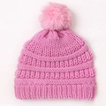 Detailed view of pink knitted baby hat with fluffy faux fur pompom and soft texture - Pink