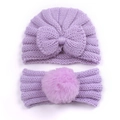 Detailed view of purple knitted baby hat with bow and matching soft pompom headband - Purple