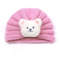 Close-up of pink knitted baby hat with soft white plush bear detail and cozy textures - Pink