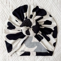 Baby tulbandmuts met zwart-witte koeprint en een decoratieve donut knoop erop - Eén maat / Stijl B (Koeprint)