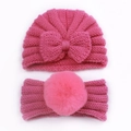 Detail of pink knitted baby hat set featuring a bow and fluffy faux fur pompom headband - Rose Red