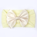 Detail van zachte baby hoofdband met een grote satijnen strik in champagne kleur - Beige