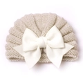 Gros plan d'un bonnet de bébé en tricot beige avec un grand nœud blanc sur fond blanc - Beige