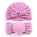 Detail of pink knitted baby beanie with bow and matching soft pom-pom headband - Pink