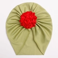 Detailed view of the ribbed knit fabric texture and large red satin flower on the baby hat - Green
