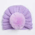 Detail van lichtpaarse gebreide babymuts met warme pompon en zachte ribbeltextuur - Paars