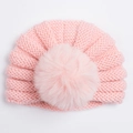 Detail van de roze gebreide baby muts met kabelpatroon en een grote zachte imitatiebont pompon - Vleesroze
