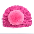 Détail d'un bonnet tricoté rose pour bébé avec un grand pompon doux et texture - Rouge Rose