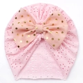 Detail der rosa gestrickten Babymütze mit großer Schleife und goldenem Punktmuster-Druck - Rosa