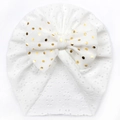 White baby turban hat featuring hollow mesh fabric and a large gold polka dot bow - White