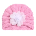 Détail d'un bonnet tricoté rose pour bébé avec une grande fleur décorative blanche - Rose
