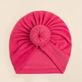 Macro detail van een rozerode baby tulband muts met donut knoop van zachte rekbare stof - Rozerood