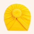 Detail of bright yellow baby donut hat with ribbed texture and round top knot - Yellow