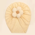 Detailed close-up of baby turban with hollow embroidery and large ribbed knit flower decoration - Beige