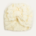 Detail of cream white baby turban hat featuring waffle texture and a large bow - Beige