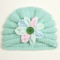 Close-up of mint green knitted baby turban with colorful 3D flower and green button detail - Mint Green