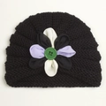 Detail of baby knitted flower hat with layered fabric petals and a large green button - Black