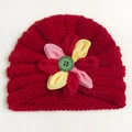 Detailed knit texture of red baby turban hat with a colorful floral and button accent - Red