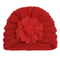 Détail d'un bonnet en tricot rouge pour bébé orné d'une grande fleur décorative multicouche - Rouge