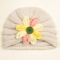 Detail of baby knitted hat with cream spiral texture and colorful floral button decor - Beige