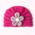 Detail der Baby-Strickmütze mit rosenroter Textur und großer Stoffblumen-Verzierung - Fuchsia