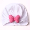 Dettaglio del turbante bianco per neonati con fiocco rosa acceso su sfondo monocromatico - Bianco