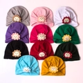 Flat lay of 11 assorted infant knotted beanies featuring cute lion and flower patches - One Size / Mixed Colors Pack