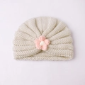 Détail du bonnet tricoté pour bébé montrant la texture douce et la fleur rose faite main - Beige Et Rose
