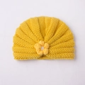 Détail d'un bonnet tricoté pour bébé avec texture plissée jaune et fleur en crochet - Jaune