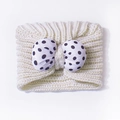 Detail van een gebreide babyhoofdband met crème ribbreisel en een grote strik met stippen - Eén maat / Beige