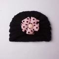 Knitted baby turban hat in black featuring a large pink polka dot decorative flower - Black