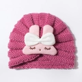 Detail of baby knitted hat featuring a cute plush bunny with embroidery and pink bow - Dusky Pink