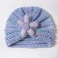 Detailed macro view of the knitted stripe texture and large decorative fabric flower on the hat - Purple